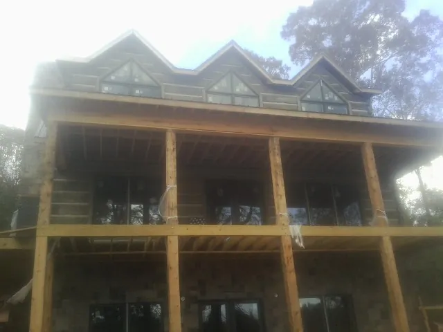 Dormers and porch framing on a large log home under construction — Roof Coating work by our crew in Pine Island