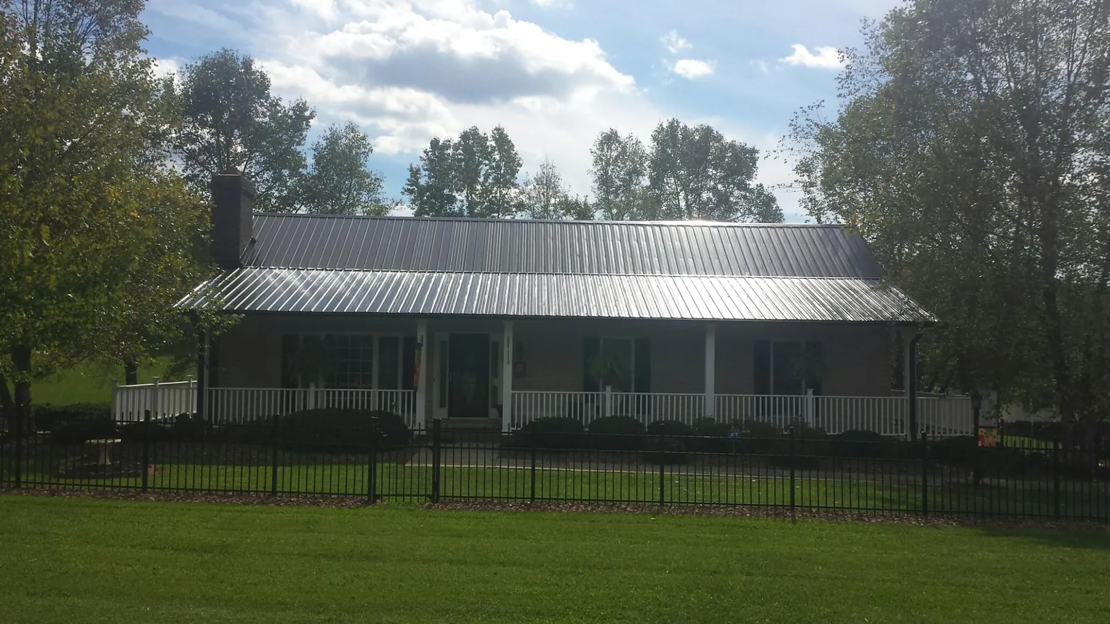Gray metal roof on a brick ranch with a full width front porch — Gutter Guard Installation work by our crew in Pine Island