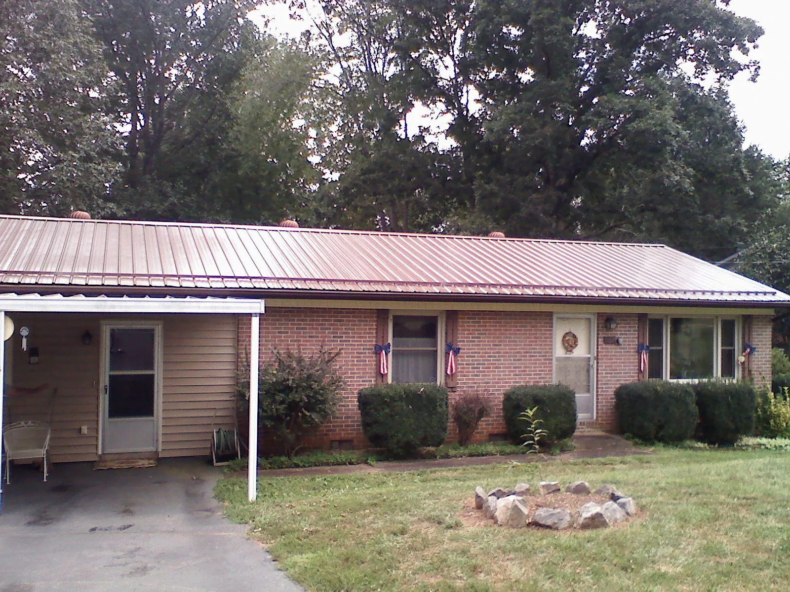 Bronze metal roof and carport on a brick ranch home — Roof Repair work by our crew in Pine Island