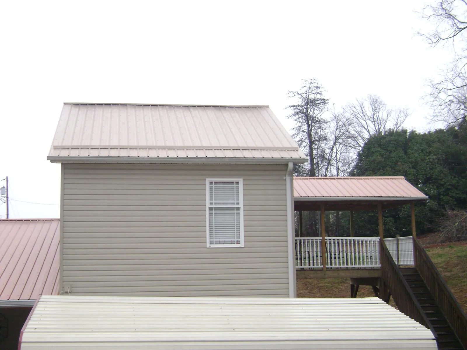 Tan metal roofs on a two story addition and attached porch, from a Roof Replacement job in Pine Island